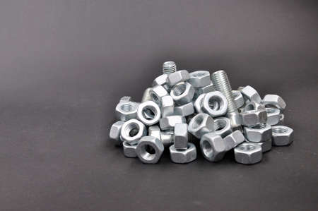 Pile of fasteners. Bolts, nuts, screws, on a black background.