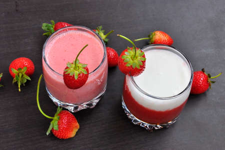 Strawberry smoothies in glass, berries on the black background