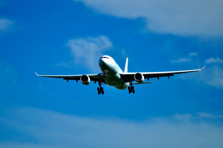 Flying plane in the blue sky with cloudsの写真素材