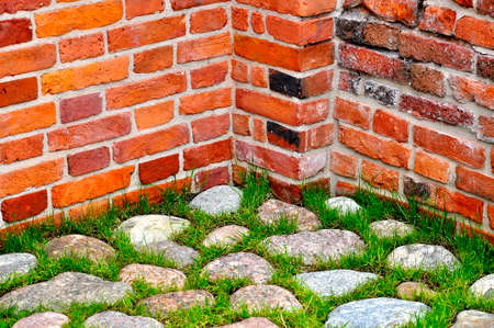 Fragment of a red brick wall and stone pavement.の写真素材