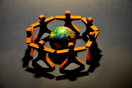 Wooden people around blue globe. Global Solution