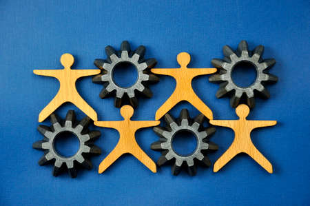 A few metal gears connected to each other and a figure of a man made of wood.の写真素材