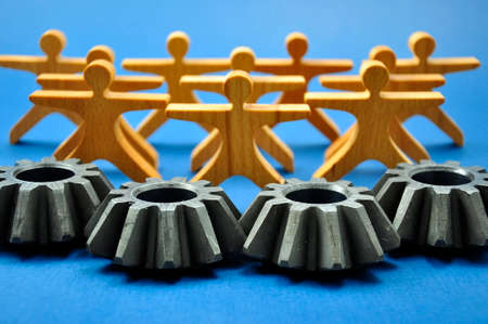 A few metal gears connected to each other and a figure of a man made of wood.の写真素材