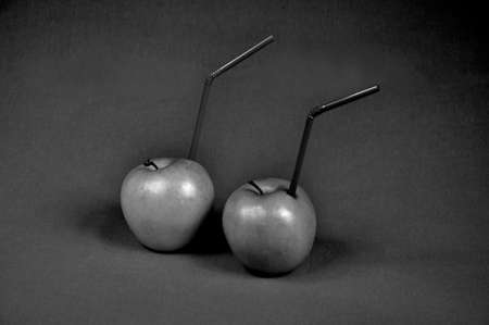 Green apple juice with a drinking straw. Monochrome photo.