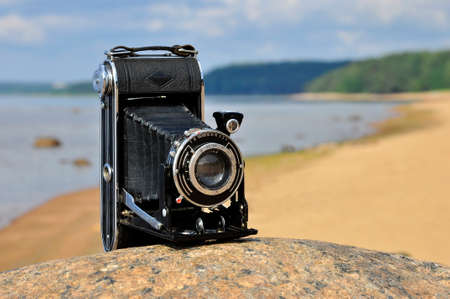 Black analog camera on the background of the sea shore