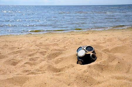 Environmental pollution. Gas mask on the sandy beach.の写真素材