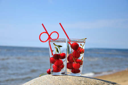 Transparent glasses of fresh cherry drink with a straw on the background of the sea.の写真素材