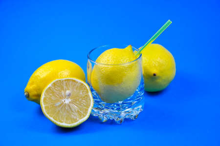 Ripe yellow lemons and a glass of lemon juice on a blue background. Banner.の写真素材