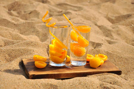Peach fresh drink with a straw on a sandy beach.の写真素材