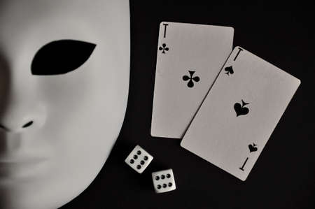 Gambler, white mask and playing cards on a black backgroundの写真素材