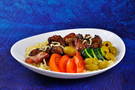 Roast pork with noodles and vegetables on a plate.の写真素材