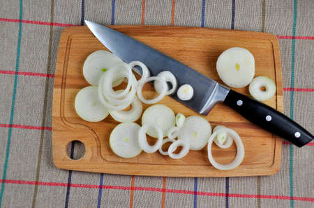 Sliced onion on a chopping board and a kitchen knife.の写真素材