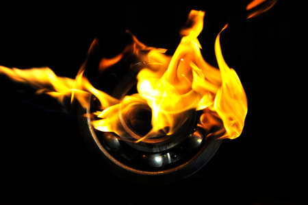 Metal ball bearing in flame on black background.の写真素材