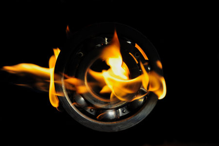 Metal ball bearing in a bright flame on a black background.の写真素材
