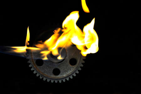Metal cog wheel in flame on black background.の写真素材