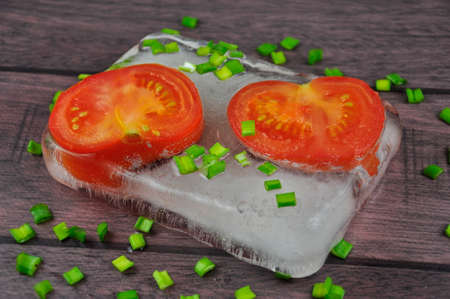 Red fresh tomatoes and green onions on a wooden table.の写真素材