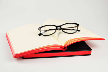 Black Eyeglasses and notepads on white background.の写真素材