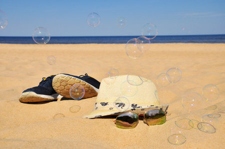 holiday. beach accessories. Sneakers, hat and sunglasses on a sandy beach.の写真素材