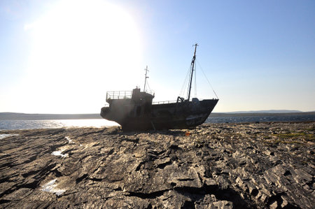 A fishing boat stranded on a rocky shore.の写真素材