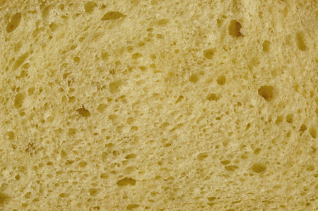 The soft and airy texture of sliced white bread is highlighted against a plain backdrop, revealing the delicate crumb and small air holes typical of fresh bread.の写真素材