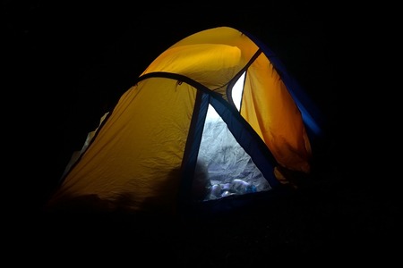 Illuminated orange camping tent at night.の写真素材