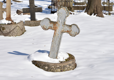 Old cross in a cemetery at sunny winter day close up.の写真素材