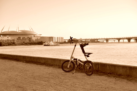 ST.PETERSBURG, RUSSIA - 11 AUGUST 2017: Bicycle Strida on embankment of Gulf of Finland.. Strida - folding bike with a memorable frame in the shape of the letter A. Sepia.のeditorial素材