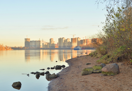 Coast of Neva River and modern residential buildings under construction on the outskirts of St. Petersburg at sunny autumn evening, Russia.の写真素材