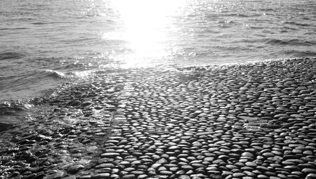 Paving stones of the embankment near the river at sunny day. Black and white.の写真素材