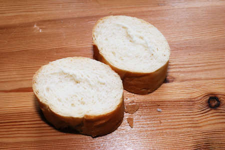 Sliced wheat baguette close up on wooden surface.