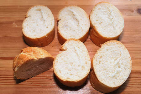 Sliced wheat baguette close up on wooden surface.