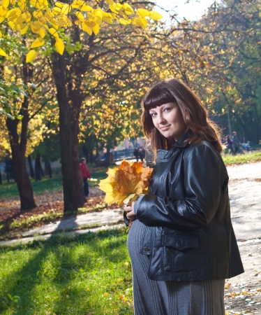 Pleasured pregnant woman in autumn park の写真素材