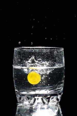 Black and white highspeed shot of an grape falling in into a glass full of water の写真素材