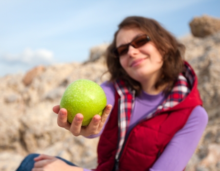 Young woman giving an apple in a nature environment  Good for dieting and healthy lifestyle issues の写真素材