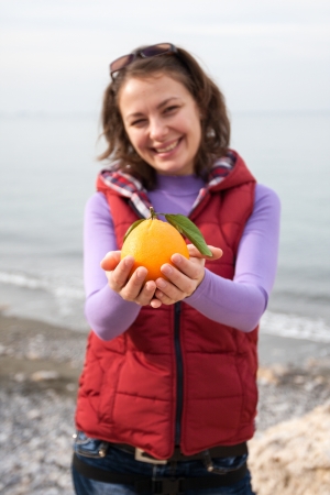 Woman holding orange in her armsの写真素材