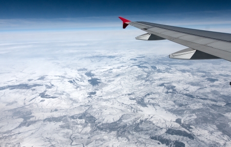 View of airplane wing abowe the clouds and landの写真素材
