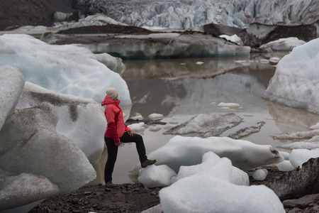 Woman in bright erd raincoat near the Glacier Lagoon, Iceland