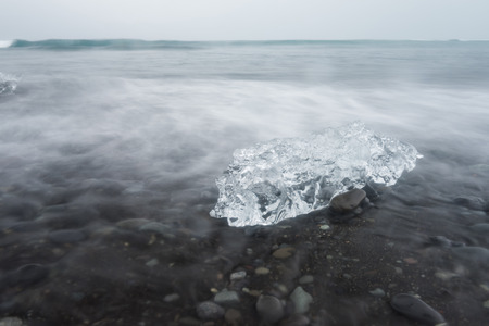 Icebergs at Jokulsarlon, Iceland. Black volcanic sand beach and blue icebergs.