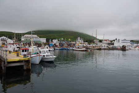Beautiful view of the historic town of Husavik with traditional colorful houses and traditional fisherman boats lying in the harbor, northern coast of Icelandの写真素材
