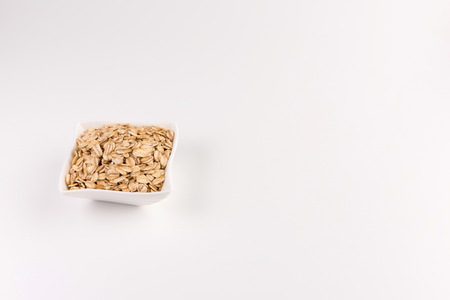 Dry rolled oatmeal in bowl isolated on white background.の写真素材