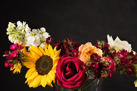 Bouquet of white yellow and red flowers in a vase on a dark backgroundの写真素材