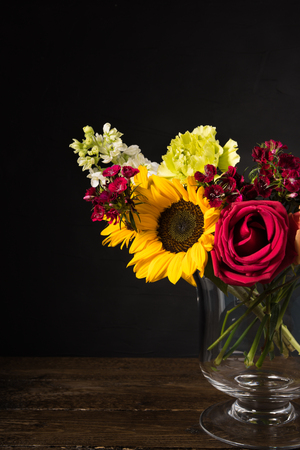 Bouquet of white yellow and red flowers in a vase on a dark backgroundの写真素材