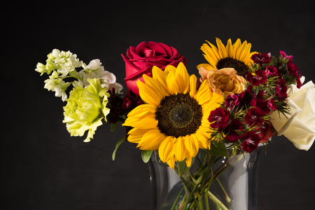 Bouquet of white yellow and red flowers in a vase on a dark backgroundの写真素材