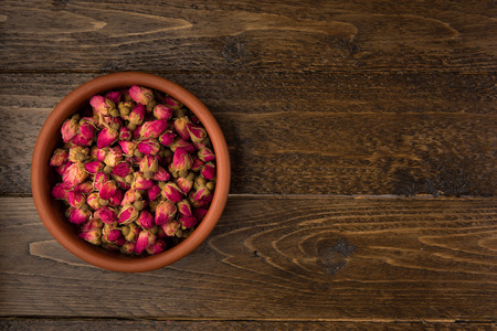tea rose buds in a clay pot  isolated on wooden background, top viewの写真素材