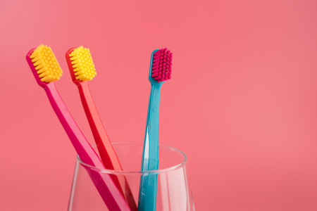 Cup with toothbrushes on table against color background. Dental careの写真素材