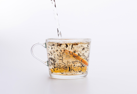 Tea pouring into glass cup isolated on whiteの写真素材