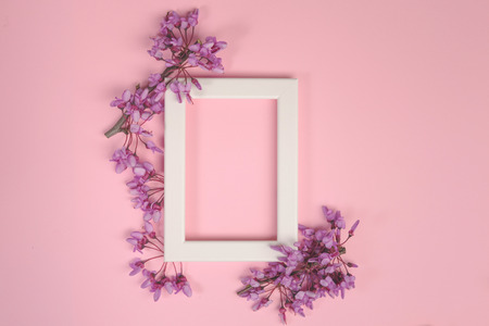 Flowers composition. Purple flowers and photo frame on pastel pink background. Flat lay, top view, copy spaceの写真素材