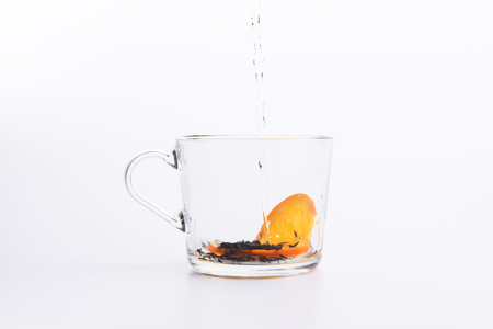 Tea pouring into glass cup isolated on whiteの写真素材