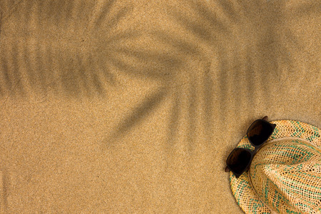Minimalist summer flat lay with, sunglasses and panama hat on sand background with shadow