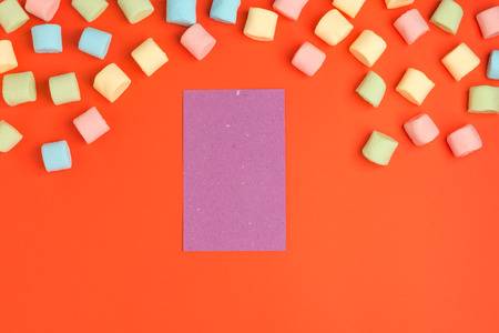 Coral paper background with marshmallow and blank notepad. Place for your text. Cozy sweet backgroundの写真素材